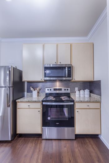 A modern kitchen with a stainless steel refrigerator, microwave, and oven.